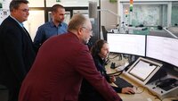 Bild vergr&ouml;&szlig;ern: Lars Oehmke (Gesch&auml;ftsf&uuml;hrer Rettungsdienst Cuxland gGmbH), Dr. Benjamin Junge (&Auml;rztlicher Leiter Rettungsdienst im Landkreis Cuxhaven) und Ulrich Bruns (Fachdienstleiter Rettungswesen beim Landkreis Goslar) blicken in der Goslarer Leitstelle Laura Jodat &uuml;ber die Schulter
